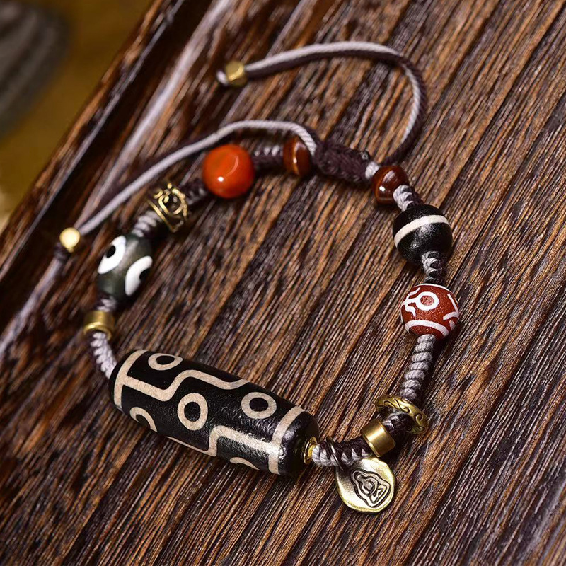 Nine-eyed dzi bead bracelet resting on a piece of driftwood