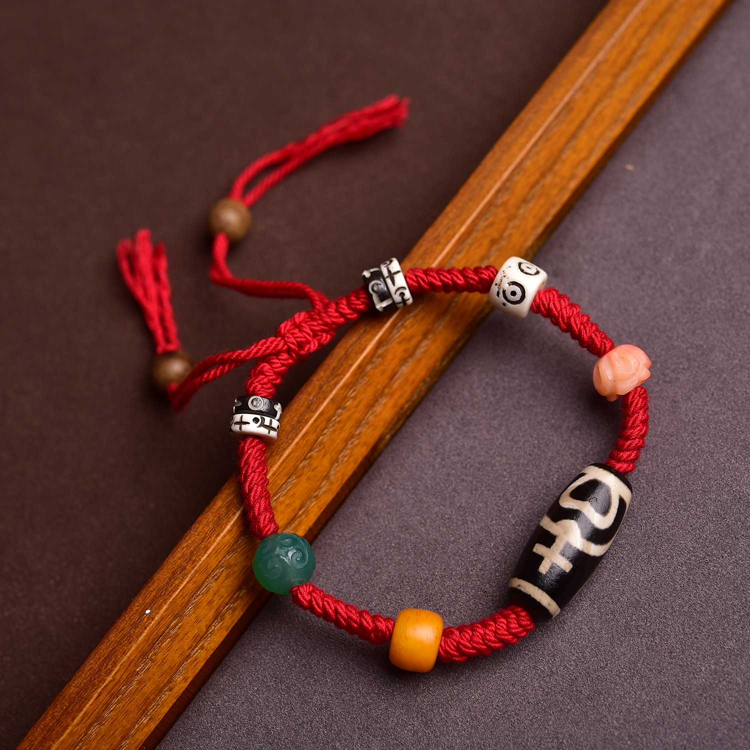 Red string bracelets resting on the edge of a wooden display tray