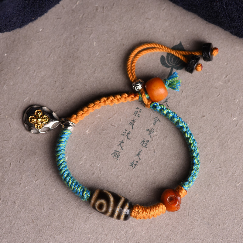 Dzi beads bracelet with alternating Tibetan cords placed on Chinese script paper