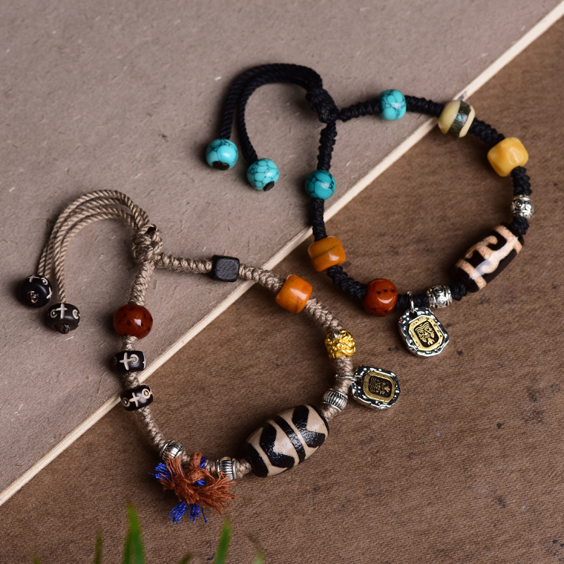 Two Dzi beads bracelets, black and gray styles, arranged at 45-degree angle