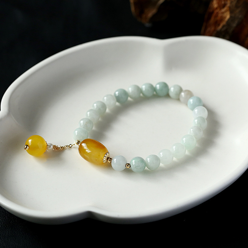 White jade and yellow agate bracelet in ceramic dish