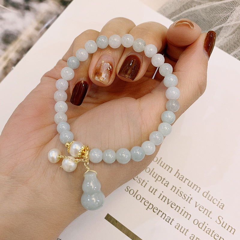 Model displaying jade bracelet in palm with white gourd tassel