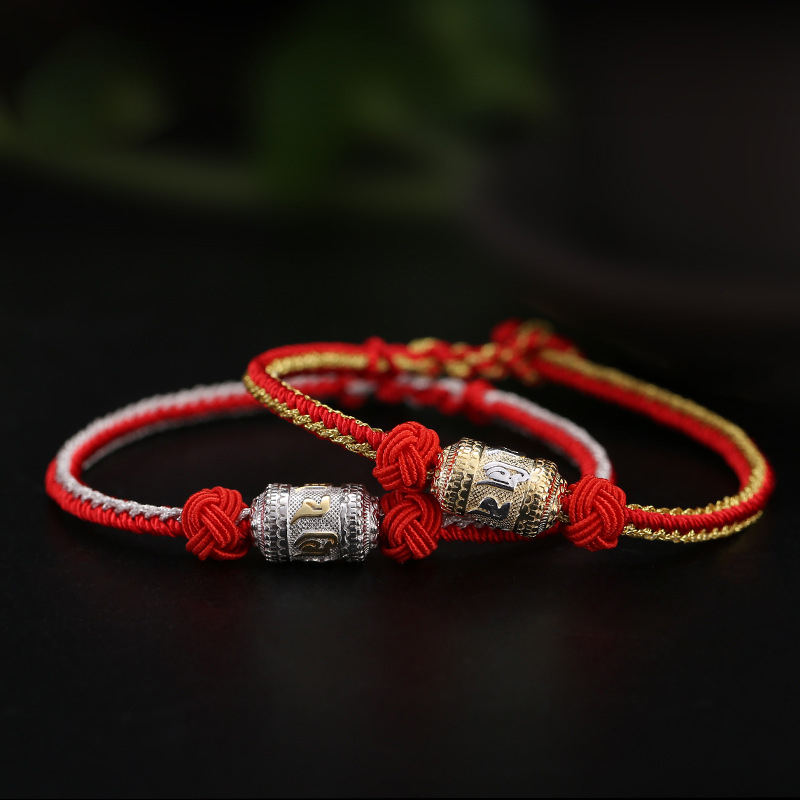 Stacked gold and silver prayer wheel bracelets with red cords