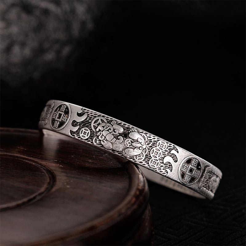 Silver Pixiu bracelet leaning against wooden tray