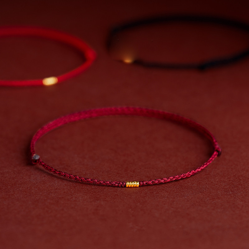 Burgundy red Tibetan string bracelet with black and red bracelets in background