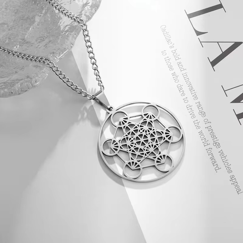 Silver Metatron's Cube Necklace placed on an open magazine