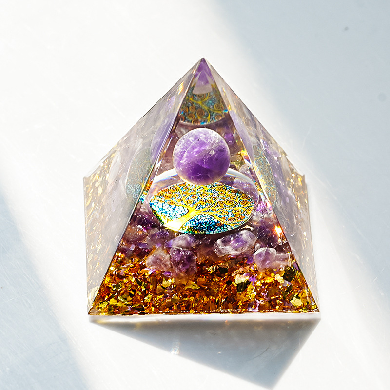 Golden Tree Amethyst orgonite pyramid shining under direct light on a white base.