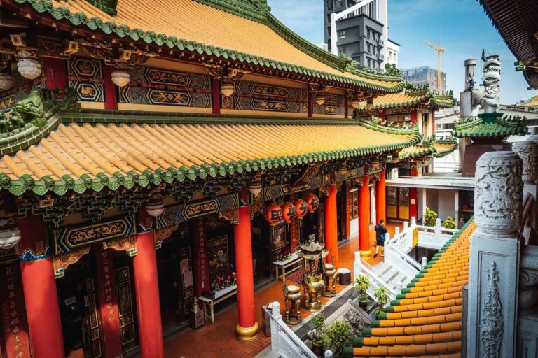 Sacred temple exterior exuding spiritual serenity, contrasted by distant modern city buildings in the background