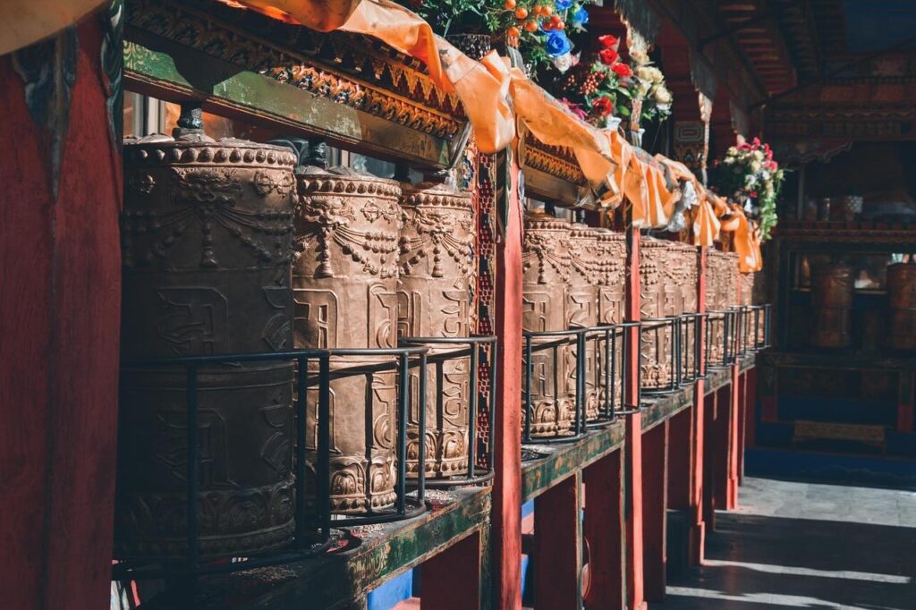 Sunlight shines on an ancient Tibetan Buddhist prayer wheel, highlighting its weathered surface and sacred engravings.